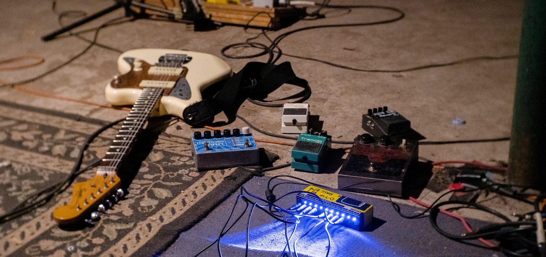 une guitare au sol avec des pedales d'effet